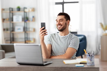 Image showing man with smartphone and laptop at home office