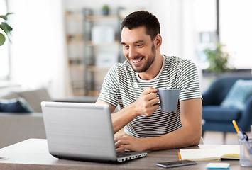 Image showing man with laptop drinking coffee at home office