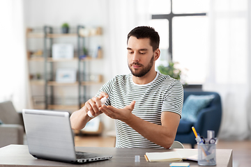 Image showing man using hand sanitizer at home office