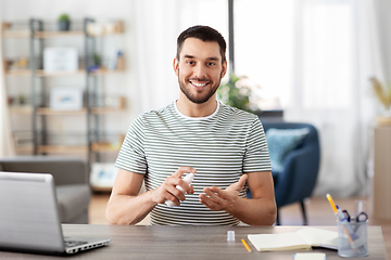 Image showing man using hand sanitizer at home office