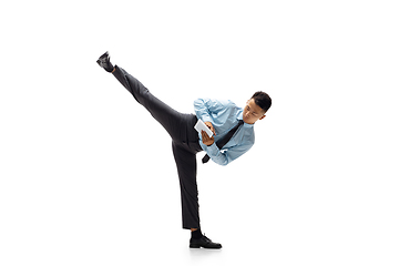 Image showing Man in office clothes practicing taekwondo on white background. Unusual look for businessman in motion, action. Sport, healthy lifestyle.