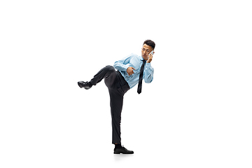 Image showing Man in office clothes practicing taekwondo on white background. Unusual look for businessman in motion, action. Sport, healthy lifestyle.