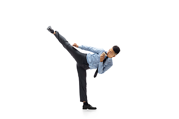 Image showing Man in office clothes practicing taekwondo on white background. Unusual look for businessman in motion, action. Sport, healthy lifestyle.