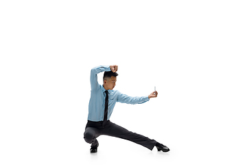 Image showing Man in office clothes practicing taekwondo on white background. Unusual look for businessman in motion, action. Sport, healthy lifestyle.