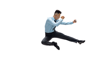 Image showing Man in office clothes practicing taekwondo on white background. Unusual look for businessman in motion, action. Sport, healthy lifestyle.