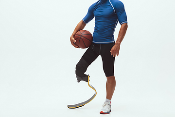 Image showing Athlete with disabilities or amputee isolated on white studio background. Professional male basketball player with leg prosthesis training and practicing in studio.