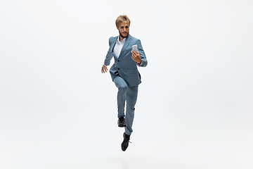 Image showing Man in office clothes running, jogging on white background. Unusual look for businessman in motion, action. Sport, healthy lifestyle.