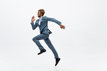 Image showing Man in office clothes running, jogging on white background. Unusual look for businessman in motion, action. Sport, healthy lifestyle.