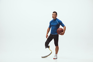 Image showing Athlete with disabilities or amputee isolated on white studio background. Professional male basketball player with leg prosthesis training and practicing in studio.