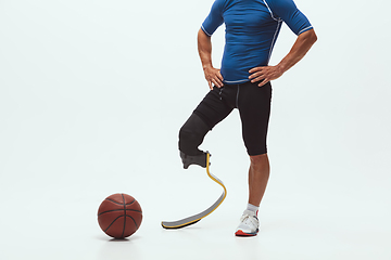 Image showing Athlete with disabilities or amputee isolated on white studio background. Professional male basketball player with leg prosthesis training and practicing in studio.