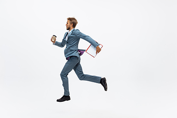 Image showing Man in office clothes running, jogging on white background. Unusual look for businessman in motion, action. Sport, healthy lifestyle.