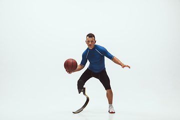 Image showing Athlete with disabilities or amputee isolated on white studio background. Professional male basketball player with leg prosthesis training and practicing in studio.