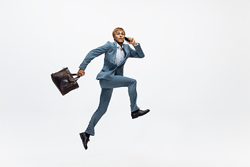 Image showing Man in office clothes running, jogging on white background. Unusual look for businessman in motion, action. Sport, healthy lifestyle.