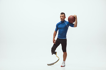 Image showing Athlete with disabilities or amputee isolated on white studio background. Professional male basketball player with leg prosthesis training and practicing in studio.