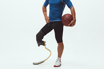 Image showing Athlete with disabilities or amputee isolated on white studio background. Professional male basketball player with leg prosthesis training and practicing in studio.