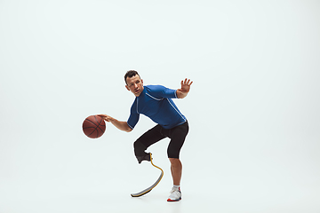 Image showing Athlete with disabilities or amputee isolated on white studio background. Professional male basketball player with leg prosthesis training and practicing in studio.