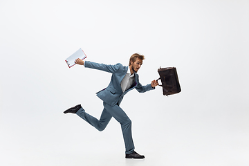 Image showing Man in office clothes running, jogging on white background. Unusual look for businessman in motion, action. Sport, healthy lifestyle.