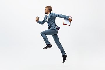 Image showing Man in office clothes running, jogging on white background. Unusual look for businessman in motion, action. Sport, healthy lifestyle.