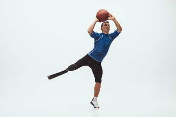 Image showing Athlete with disabilities or amputee isolated on white studio background. Professional male basketball player with leg prosthesis training and practicing in studio.