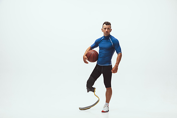 Image showing Athlete with disabilities or amputee isolated on white studio background. Professional male basketball player with leg prosthesis training and practicing in studio.