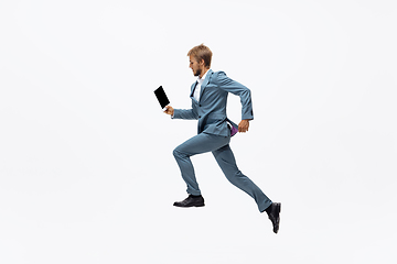 Image showing Man in office clothes running, jogging on white background. Unusual look for businessman in motion, action. Sport, healthy lifestyle.