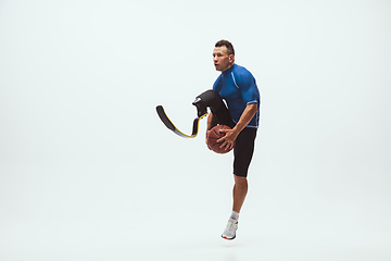 Image showing Athlete with disabilities or amputee isolated on white studio background. Professional male basketball player with leg prosthesis training and practicing in studio.