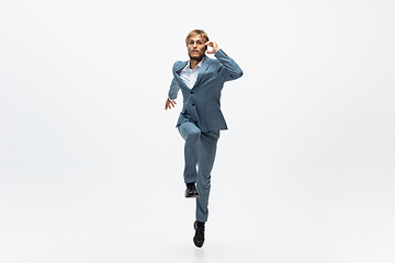 Image showing Man in office clothes running, jogging on white background. Unusual look for businessman in motion, action. Sport, healthy lifestyle.