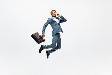 Image showing Man in office clothes running, jogging on white background. Unusual look for businessman in motion, action. Sport, healthy lifestyle.