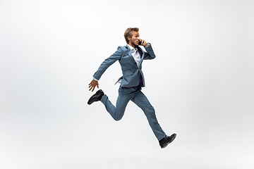 Image showing Man in office clothes running, jogging on white background. Unusual look for businessman in motion, action. Sport, healthy lifestyle.