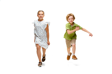 Image showing Happy little caucasian girl and boy jumping and running isolated on white background