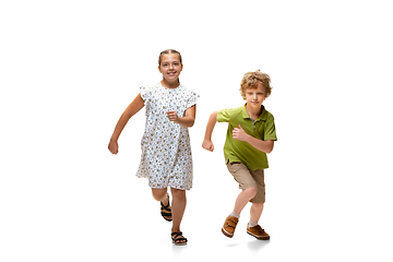 Image showing Happy little caucasian girl and boy jumping and running isolated on white background