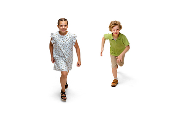 Image showing Happy little caucasian girl and boy jumping and running isolated on white background