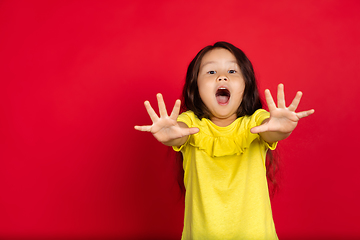 Image showing Beautiful emotional little girl isolated on red background. Half-lenght portrait of happy child gesturing