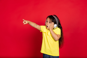 Image showing Beautiful emotional little girl isolated on red background. Half-lenght portrait of happy child gesturing