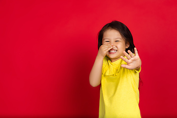 Image showing Beautiful emotional little girl isolated on red background. Half-lenght portrait of happy child gesturing