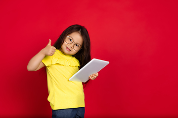 Image showing Beautiful emotional little girl isolated on red background. Half-lenght portrait of happy child gesturing