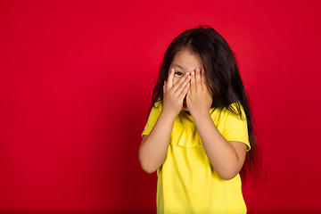 Image showing Beautiful emotional little girl isolated on red background. Half-lenght portrait of happy child gesturing