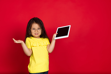 Image showing Beautiful emotional little girl isolated on red background. Half-lenght portrait of happy child gesturing