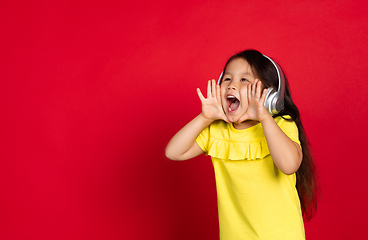 Image showing Beautiful emotional little girl isolated on red background. Half-lenght portrait of happy child gesturing