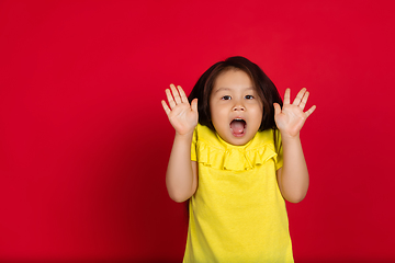 Image showing Beautiful emotional little girl isolated on red background. Half-lenght portrait of happy child gesturing