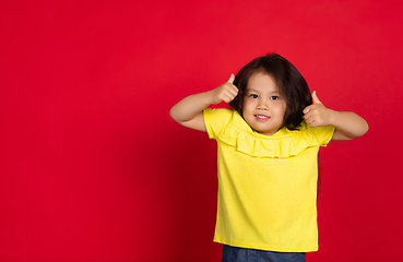 Image showing Beautiful emotional little girl isolated on red background. Half-lenght portrait of happy child gesturing