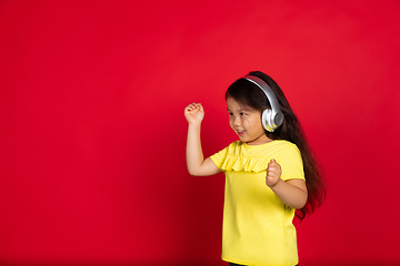 Image showing Beautiful emotional little girl isolated on red background. Half-lenght portrait of happy child gesturing