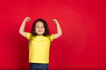 Image showing Beautiful emotional little girl isolated on red background. Half-lenght portrait of happy child gesturing