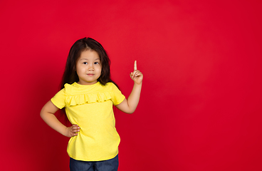 Image showing Beautiful emotional little girl isolated on red background. Half-lenght portrait of happy child gesturing