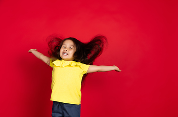 Image showing Beautiful emotional little girl isolated on red background. Half-lenght portrait of happy child gesturing