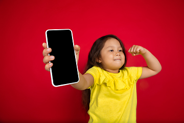 Image showing Beautiful emotional little girl isolated on red background. Half-lenght portrait of happy child gesturing