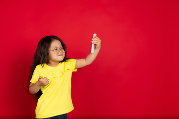 Image showing Beautiful emotional little girl isolated on red background. Half-lenght portrait of happy child gesturing