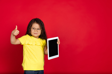 Image showing Beautiful emotional little girl isolated on red background. Half-lenght portrait of happy child gesturing