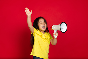 Image showing Beautiful emotional little girl isolated on red background. Half-lenght portrait of happy child gesturing