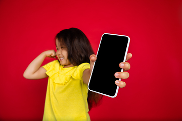 Image showing Beautiful emotional little girl isolated on red background. Half-lenght portrait of happy child gesturing